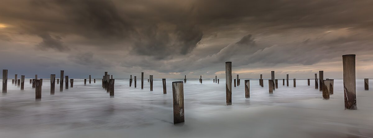 CW6984962: Verweerde palen in bewolkt water