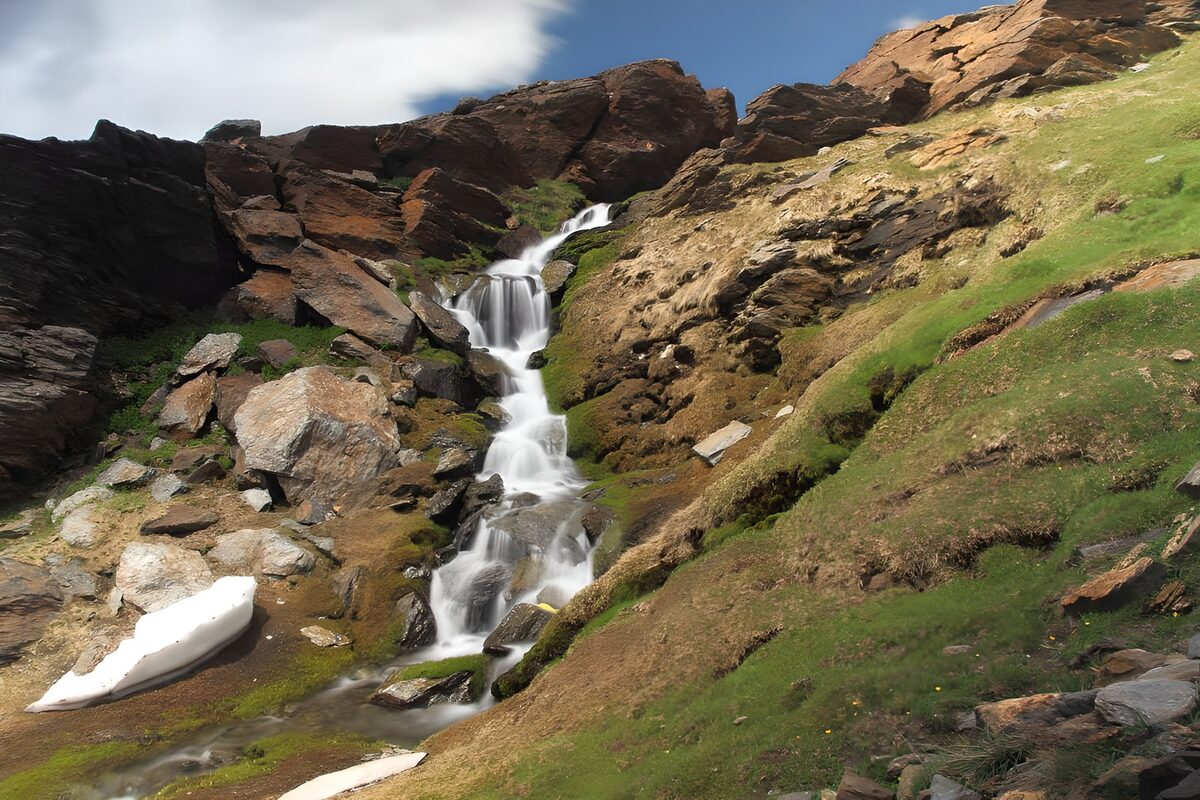 Waterval tussen rotsen en gras