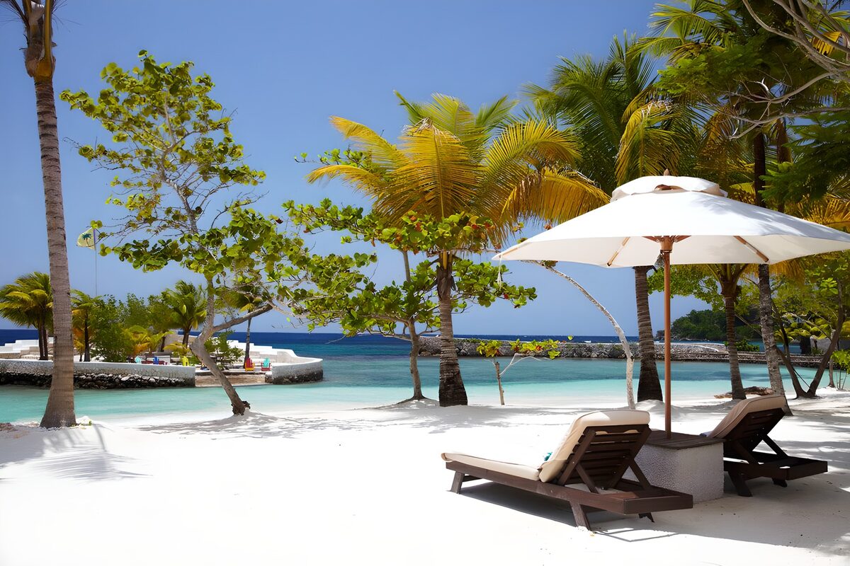 CW4727071: Tropisch strand met ligbedden en parasol
