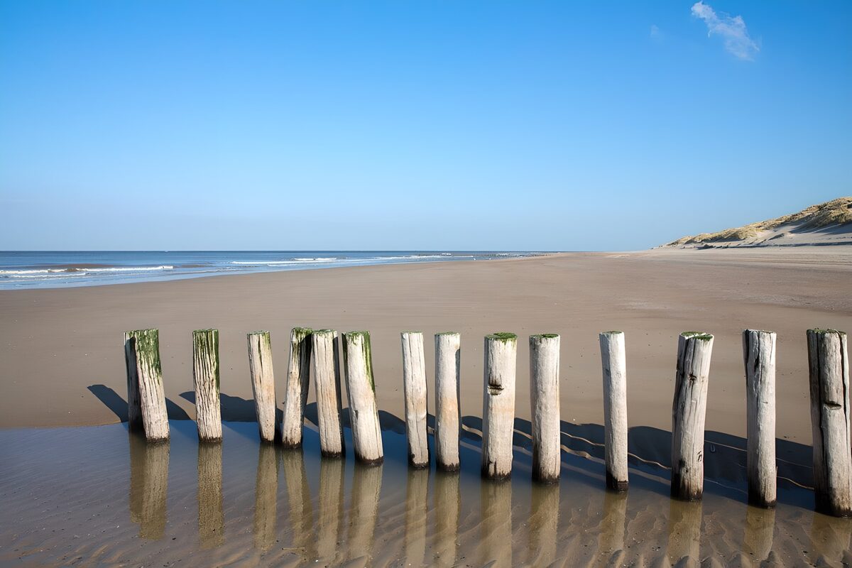 CW1857248: Rustig strand met houten palen