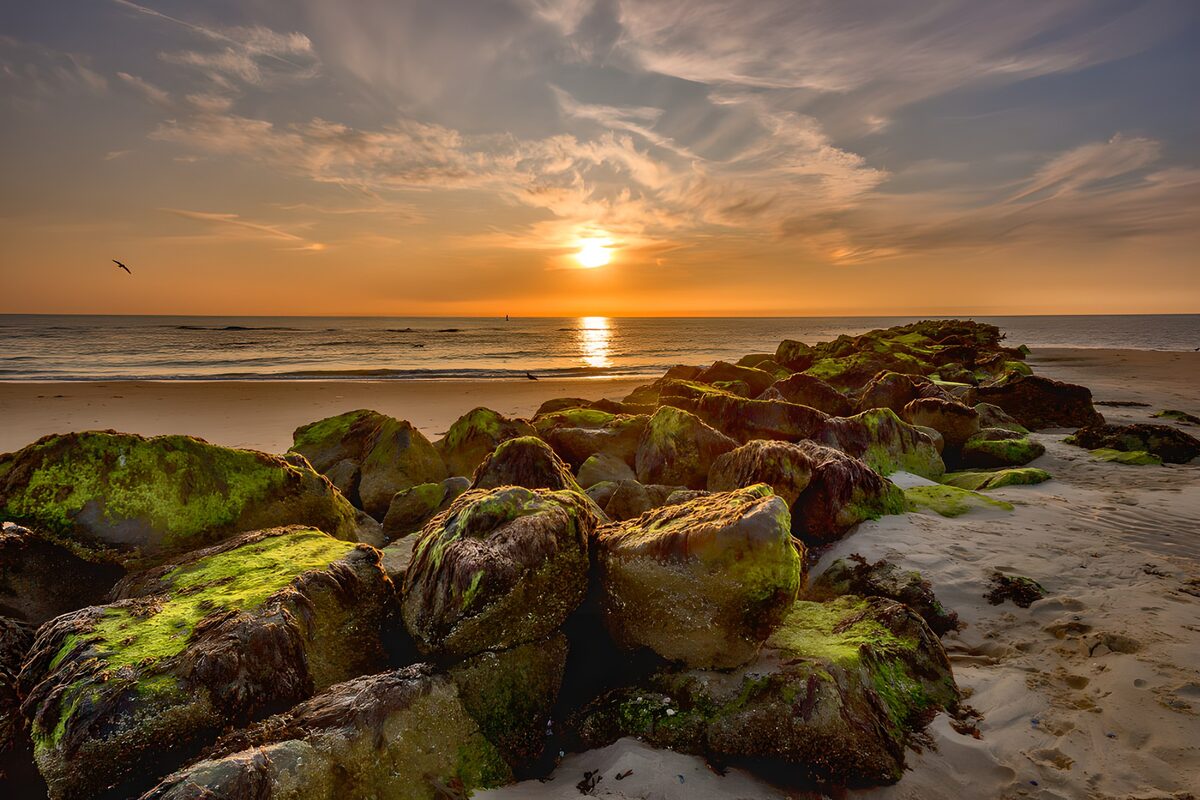 Zonsondergang boven rotsen aan het strand