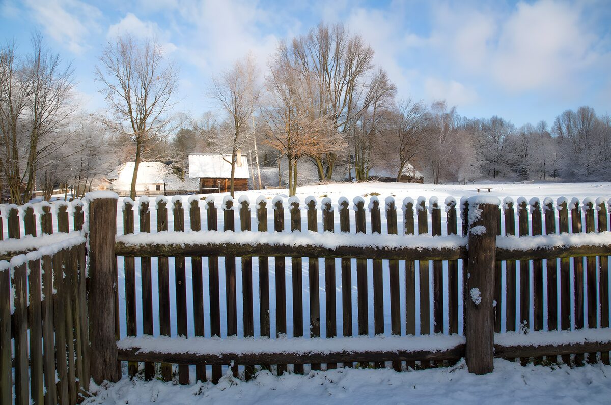 Sneeuwbedekte tuin met houten hek